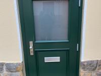 Grüne Holzhaustür mit halbseitigem Lichtausschnitt Außenansicht