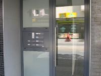 Glas-Haustür mit grauem Rahmen und Seitenteil mit Briefkastenanlage