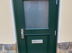 Grüne Holzhaustür mit halbseitigem Lichtausschnitt Außenansicht