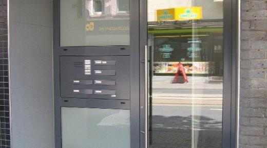 Glas-Haustür mit grauem Rahmen und Seitenteil mit Briefkastenanlage 