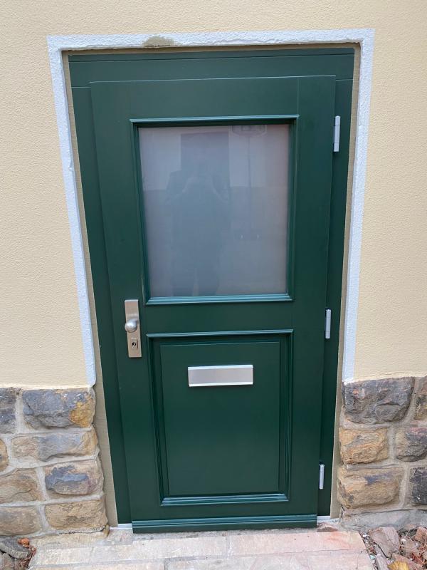 Grüne Holzhaustür mit halbseitigem Lichtausschnitt Außenansicht